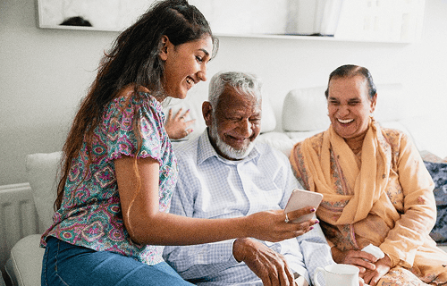 Interação entre jovem e idosos em ambiente acolhedor, representando compromisso da AstraZeneca com sustentabilidade, saúde da sociedade e bem-estar comunitário